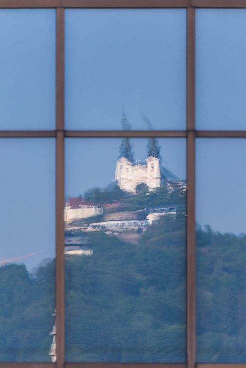 Église de pèlerinage reflétée dans les fenêtres d'un bâtiment à Linz